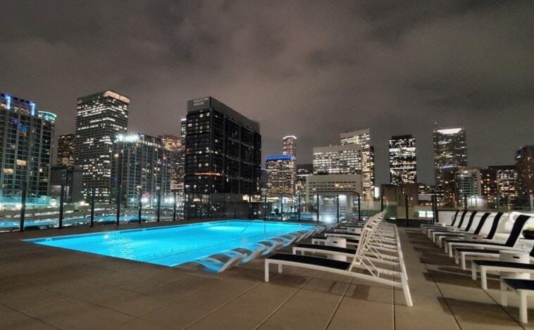 Rooftop pool of Eighteen25 Downtown Apartments illuminated at night with the Houston skyline in the background.