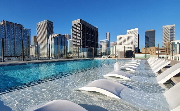 Sunny day view of Eighteen25 Downtown's rooftop pool with the downtown Houston skyline.